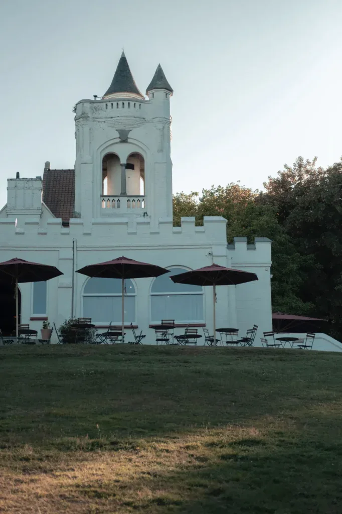 Het iconische witte gebouw van The Famous Belvedere met toren en terras, gelegen in een groene omgeving